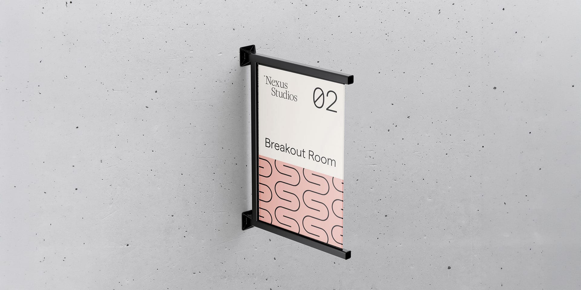 A modern room identification sign mounted on a textured grey concrete wall. The sign is in a portrait orientation and housed within a black metal frame. At the top, the sign displays the logo "Nexus Studios" followed by the number "02" in large, bold type. Below this, the text "Breakout Room" is printed in a smaller, elegant serif font. The bottom third of the sign showcases a distinctive pink background with an abstract, looping line pattern in a pink shade. This design element adds a playful yet sophisticated touch to the overall minimalist and clean aesthetic of the signage.